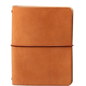 Puede incluir: Una funda para cuaderno de cuero color canela con esquinas redondeadas y un acabado mate suave. La funda está asegurada por una banda elástica fina del mismo color que se envuelve horizontalmente alrededor del centro, sujetando los paneles.