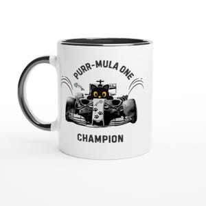 May include: White ceramic mug with a black rim and handle. The mug features a black and white illustration of a race car with a cat driver and the text "Purr-Mula One Champion."