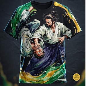 Peut inclure: Un t-shirt noir à manches courtes avec une illustration graphique de deux pratiquants d'arts martiaux en uniforme blanc effectuant une projection. Le motif inclut des éclaboussures style aquarelle verte et jaune et des kanjis japonais.