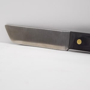 May include: A stainless steel knife with a black handle and two gold accents. The knife has a slightly curved blade.