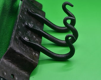 May include: Black metal wall mounted hook rack with three hooks. The hooks are curled at the ends.