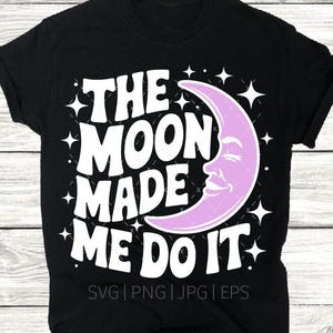 May include: Black t-shirt with the phrase "THE MOON MADE ME DO IT" in white, with a light purple crescent moon graphic. The design includes white stars and the file types SVG, PNG, JPG, and EPS.