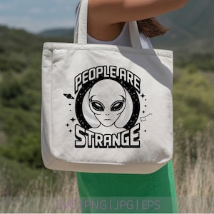 Puede incluir: Un bolso de tela blanco con un estampado gráfico negro de una cabeza alienígena centrada en un marco circular. El texto "PEOPLE ARE STRANGE" está impreso en letras negras en negrita sobre y debajo del alienígena, junto a estrellas y un planeta.