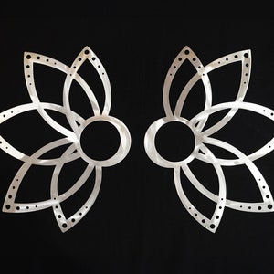 May include: A pair of silver metal earrings shaped like a flower with a circular cutout in the centre. The earrings have a delicate, intricate design.