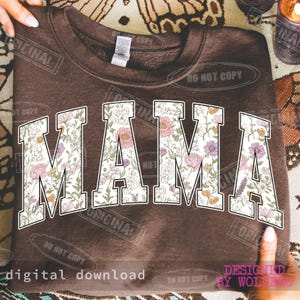 May include: A brown sweatshirt with the word "MAMA" in large, floral-patterned letters. The sweatshirt has a crew neck and long sleeves. The design includes the text "digital download" and "designed by wolfing".