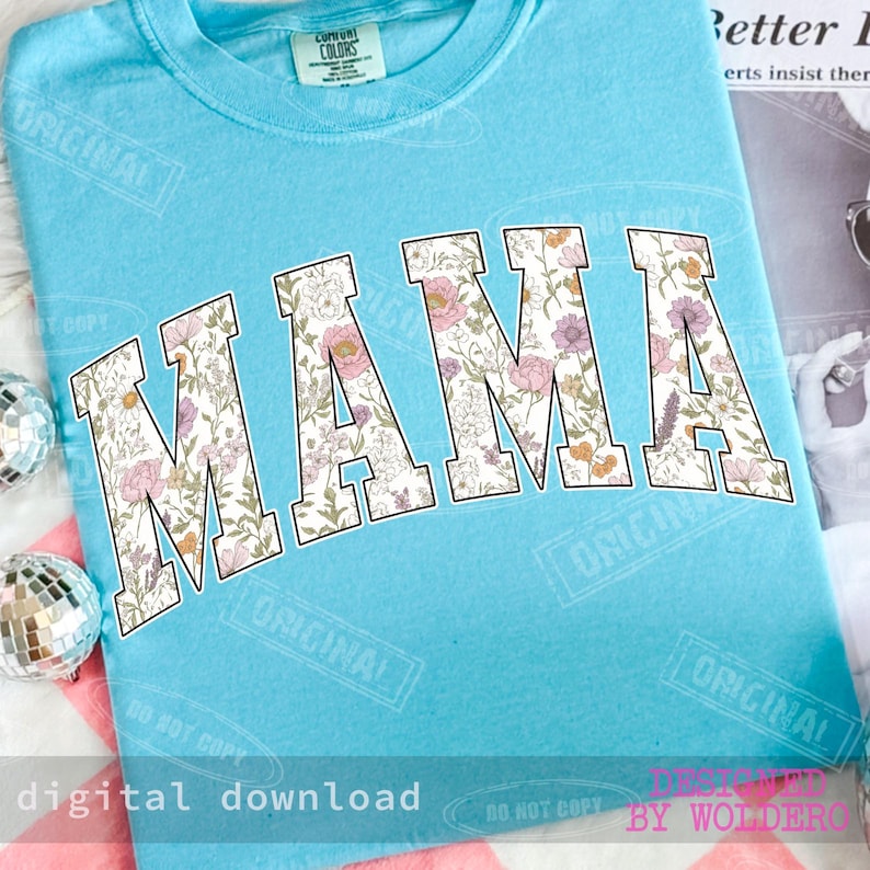 May include: A light blue t-shirt with the word "MAMA" in large, floral-patterned letters. The floral design includes pink, purple, and yellow flowers. The shirt has a crew neck and the text "digital download" is at the bottom.