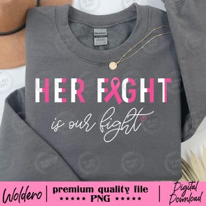 May include: A gray sweatshirt with the text "HER FIGHT is our fight" in white and pink. A pink ribbon is incorporated into the word "FIGHT". A gold necklace with a round pendant is visible.