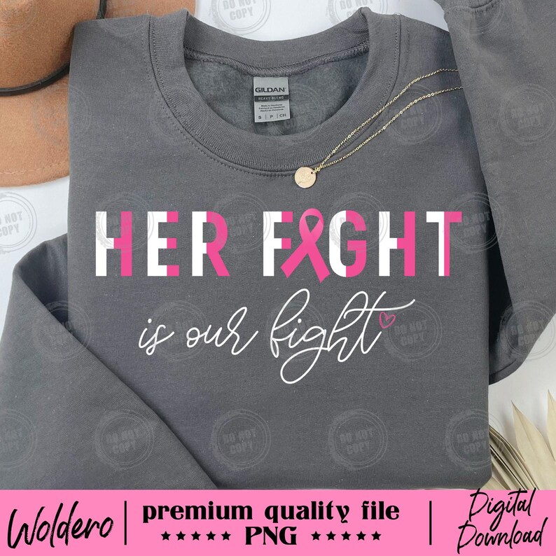 May include: A gray sweatshirt with the text "HER FIGHT is our fight" in white and pink. A pink ribbon is incorporated into the word "FIGHT". A gold necklace with a round pendant is visible.