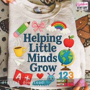 May include: A light beige sweatshirt with the phrase "Helping Little Minds Grow" in blue embroidery. The design includes a pencil, bow, rainbow, coffee cup, apple, globe, books, and a caterpillar. The words "digital download" are also visible.