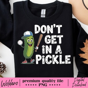 May include: Black sweatshirt with the phrase "DON'T GET IN A PICKLE" in white block letters. A cartoon pickle wearing a baseball cap and holding a baseball and bat is on the left. The bottom of the image has text that reads "premium quality file PNG".