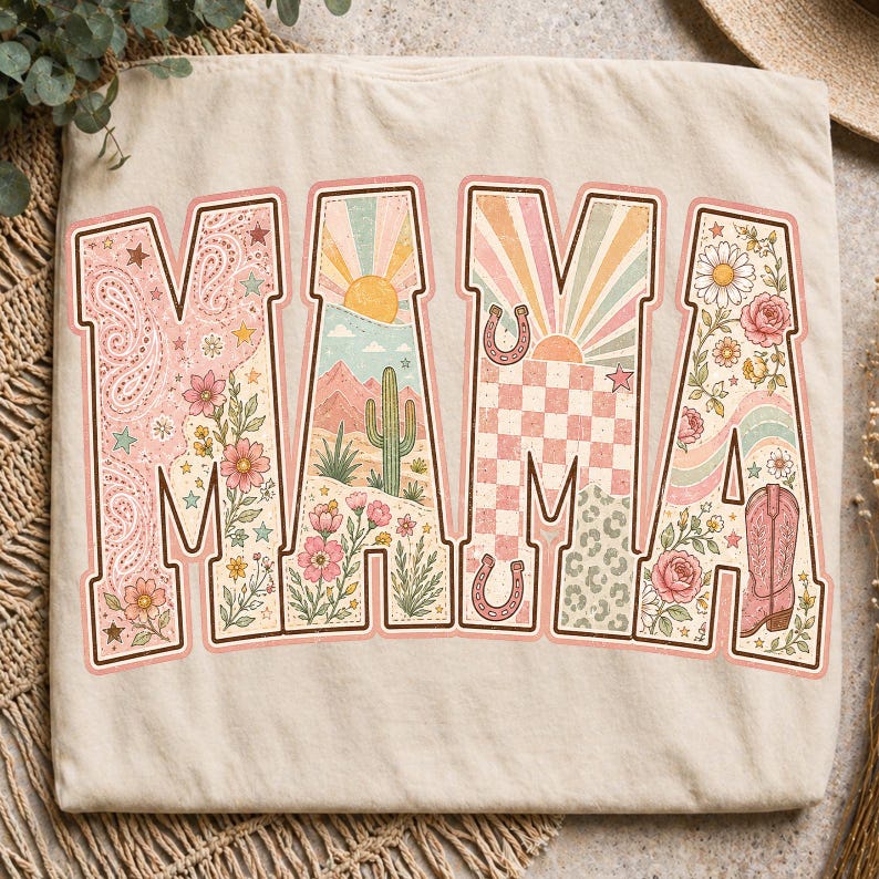 Puede incluir: Una camiseta beige con la palabra MAMA en letras grandes de bloque. Cada letra contiene un dise&ntilde;o gr&aacute;fico diferente que incluye patrones de cachemira, paisajes des&eacute;rticos con cactus, rayos de sol, cuadros, motivos florales y una bota vaquera.