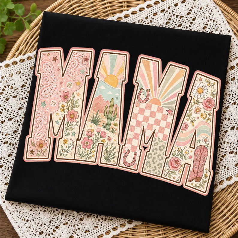 Puede incluir: Una camiseta negra con la palabra MAMA en letras grandes de bloque. Cada letra contiene un dise&ntilde;o gr&aacute;fico diferente que incluye patrones de cachemira, paisajes des&eacute;rticos con cactus, rayos de sol, cuadros, herraduras y motivos florales.