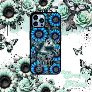 May include: A smartphone case featuring a sea turtle centred among vibrant blue sunflowers and mandala patterns. The text "May the BRIDGES I BURN light the way" is printed in the centre. The background displays mint green roses and butterflies.