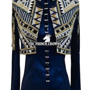 May include: A navy blue jacket with elaborate embellishments. The jacket features a high collar and is adorned with gold, silver, and black geometric patterns. The text "THE FRENCH CROWNS" is visible on the front. The jacket has long sleeves and a tailored fit.