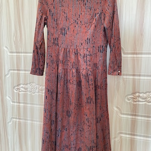 May include: A long-sleeved dress with a brown and black abstract print. The dress has a round neckline and a slightly flared skirt.