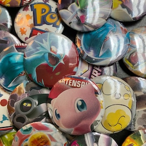 Può includere: Una collezione di bottoni colorati con personaggi di Pokemon. I bottoni presentano vari personaggi di Pokemon, tra cui Pikachu, Charizard e Mewtwo. I bottoni sono in metallo e hanno una finitura lucida.