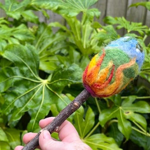 Main picture of the Beltane beater head representing the fire in the earth driving the energy for growth, blue skies and green shoots of fertility as crops sprout forth, with wite buds representing purity, cleansing and connection to ancestors.