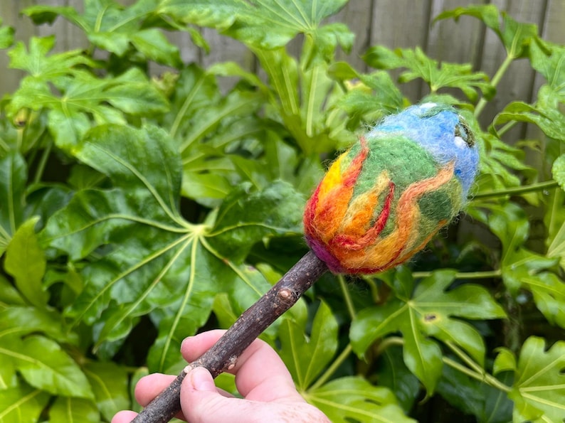 Main picture of the Beltane beater head representing the fire in the earth driving the energy for growth, blue skies and green shoots of fertility as crops sprout forth, with wite buds representing purity, cleansing and connection to ancestors.