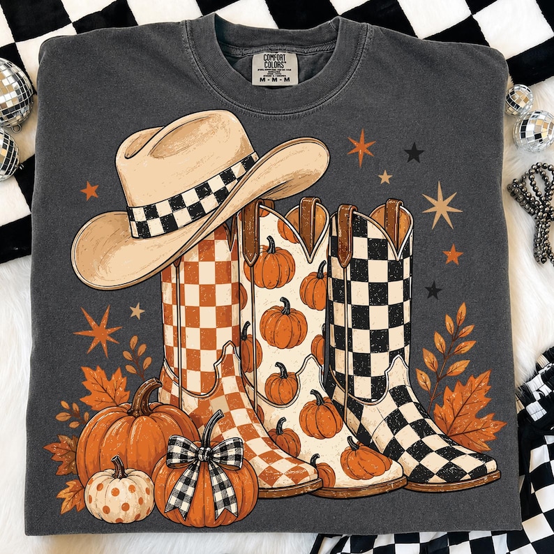 May include: A charcoal gray crewneck sweatshirt featuring a graphic print of a beige cowboy hat with a checkered band, three cowboy boots with orange checkered, pumpkin, and black checkered patterns, pumpkins, and orange autumn leaves.