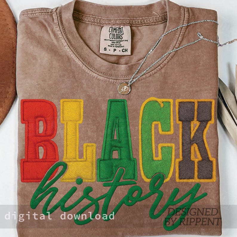 May include: A brown Comfort Colors t-shirt with the words "BLACK HISTORY" embroidered in red, yellow, green, and brown. The words "digital download" and "designed by Rippent" are also visible. A silver necklace with a pendant rests on the shirt.
