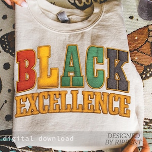 May include: A folded, light beige sweatshirt with the words "BLACK EXCELLENCE" in colorful, embroidered letters. The text is in red, yellow, green, and black. The words "digital download" and "DESIGNED BY RIPPENT" are also visible.
