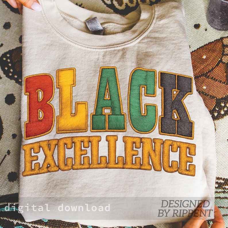 May include: A folded, light beige sweatshirt with the words "BLACK EXCELLENCE" in colorful, embroidered letters. The text is in red, yellow, green, and black. The words "digital download" and "DESIGNED BY RIPPENT" are also visible.