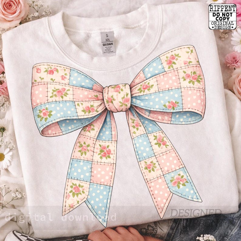 May include: White sweatshirt featuring a large bow design. The bow is a patchwork of pink, blue, and cream squares, adorned with floral patterns. The sweatshirt has a crew neck and a small size tag.