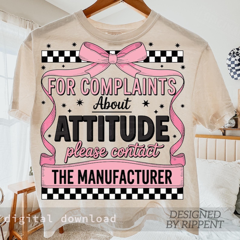 May include: Cream-colored t-shirt with a pink bow and the text "FOR COMPLAINTS ABOUT ATTITUDE please contact THE MANUFACTURER". The design includes black and white checkered patterns and stars.
