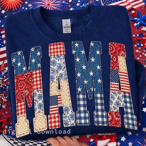 May include: A navy blue sweatshirt with the word "MAMA" appliqued across the front. The letters are patchwork, featuring patterns like stars, floral prints, and the American flag. The sweatshirt is surrounded by patriotic decorations.