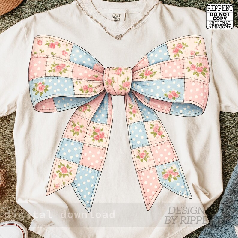May include: White t-shirt featuring a large bow design. The bow is made of patchwork squares in pink and blue, decorated with floral patterns. The shirt has a crew neck and short sleeves. The text "Comfort Colors" is visible.