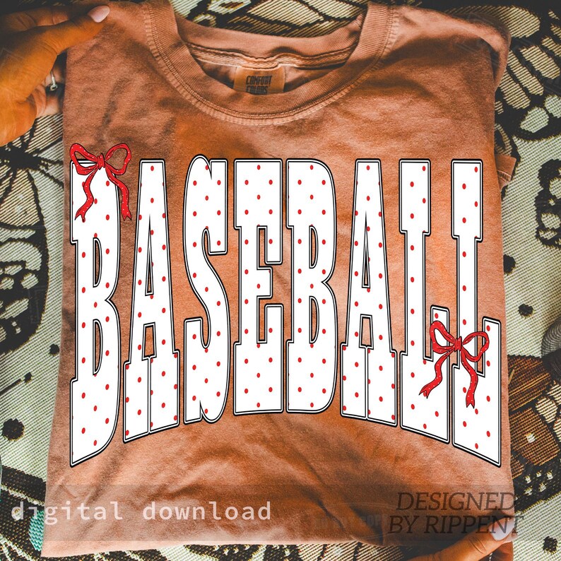 May include: A terracotta-colored t-shirt with the word "BASEBALL" in large white letters filled with red polka dots. Red bows accent the top and bottom of the word. The words "digital download" and "DESIGNED BY RIPPENT" are printed at the bottom.