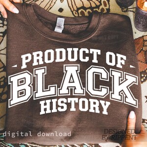 May include: A brown sweatshirt with the text "PRODUCT OF BLACK HISTORY" in white block letters. The words are stacked, with "BLACK" in a larger font size. The phrase "digital download" is at the bottom left.