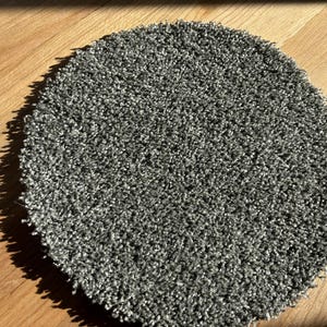 May include: A round, gray, fluffy rug with a soft, plush texture.
