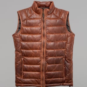 Könnte beinhalten: Eine braune Leder-Steppweste mit Reißverschluss. Die Weste hat ein gestepptes Design und einen Stehkragen.