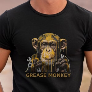 May include: A black t-shirt with a graphic of a monkey covered in yellow paint holding wrenches. The text "Grease Monkey" is printed below the monkey.