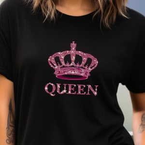 May include: Black t-shirt with a pink glitter crown and the word "QUEEN" in pink glitter.