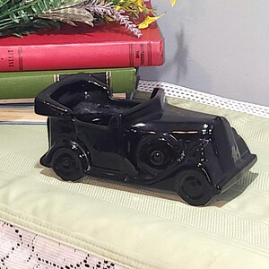 May include: A black ceramic vintage car planter. The car has a detailed design and is perfect for displaying small plants or flowers.