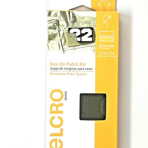 Op de afbeelding: Een opnaaiset in een gele en witte doos. De doos heeft een patch met het nummer "22" en de tekst "Sew On Patch Kit". De kit bevat een rechthoekige patch van 30,4 cm x 10,1 cm.