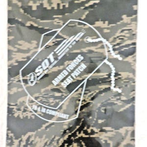 May include: A camouflage-patterned seat patch with a white outline of a dog tag. The dog tag reads "SOT ARMED FORCES SEAT PATCH" with the text "FB & IR COMPLIANT" below. A chain is attached to the dog tag.