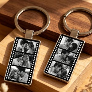 Puede incluir: Dos llaveros rectangulares de metal con diseño de tira de película. Cada llavero muestra tres fotografías en blanco y negro de una pareja en secuencia vertical. Los llaveros tienen un acabado plateado pulido y una anilla de metal.