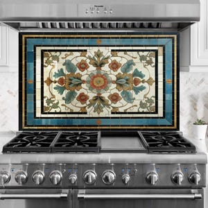 Könnte beinhalten: Dekorative Küchenrückwand mit floralem Design. Die Rückwand zeigt ein zentrales Blumenmotiv in Orange, Blau und Grün, umrahmt von einem blauen Rand. Sie befindet sich über einem Gasherd aus Edelstahl.