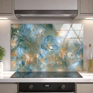 May include: A rectangular kitchen backsplash panel featuring a printed design of translucent blue and cream-colored flowers with delicate gold-toned stems and leaves. The artwork displays a soft, layered floral composition with light reflections.