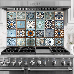 May include: A kitchen backsplash with a grid of square tiles, each displaying detailed geometric patterns in blue, white, and brown. The tiles are above a stainless steel gas hob.