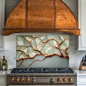 May include: A kitchen range with a copper range hood. The backsplash features a tree branch design with gold-colored outlines and white and light green sections. The stove has six burners and a stainless steel finish.