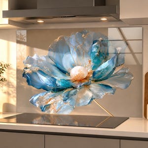 May include: A rectangular glass kitchen backsplash panel featuring a large, abstract blue and white flower design with gold-toned veining. The artwork displays layered, translucent petals in shades of teal, azure, and white, centered around a soft, glowing white core, mounted behind a black stovetop.
