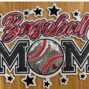 May include: A decorative patch with the words "Baseball MOM" in a script font and block letters. The word "Baseball" is in red sequins, and "MOM" is in black sequins. A baseball with red stitching is in the center, surrounded by black stars.