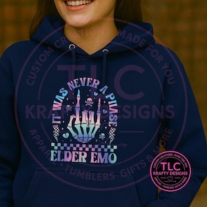 May include: Navy blue hoodie with a graphic that reads "IT WAS NEVER A PHASE" with a skeleton hand, skulls, and the words "ELDER EMO". The design is in pastel colors and has a checkered pattern.