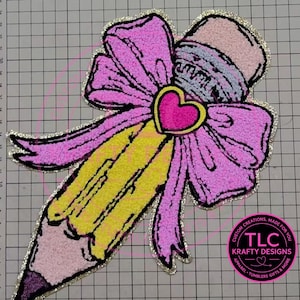 May include: A decorative pencil design with a pink bow and heart. The pencil is yellow with a pink eraser and a purple tip. The bow and heart are pink with gold glitter trim. The design includes the text "TLC Krafty Designs".