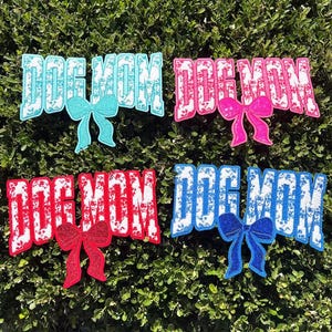 May include: Four colorful "Dog Mom" patches with glittery bow accents. The patches are in blue, pink, red, and blue, each with a matching bow. The text is in a bold, distressed font, perfect for pet lovers.