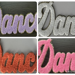 May include: Four colorful, embroidered "Dancer" patches. The patches are in lavender, white, orange, and pink, with gold trim. The patches are made of a fuzzy material.